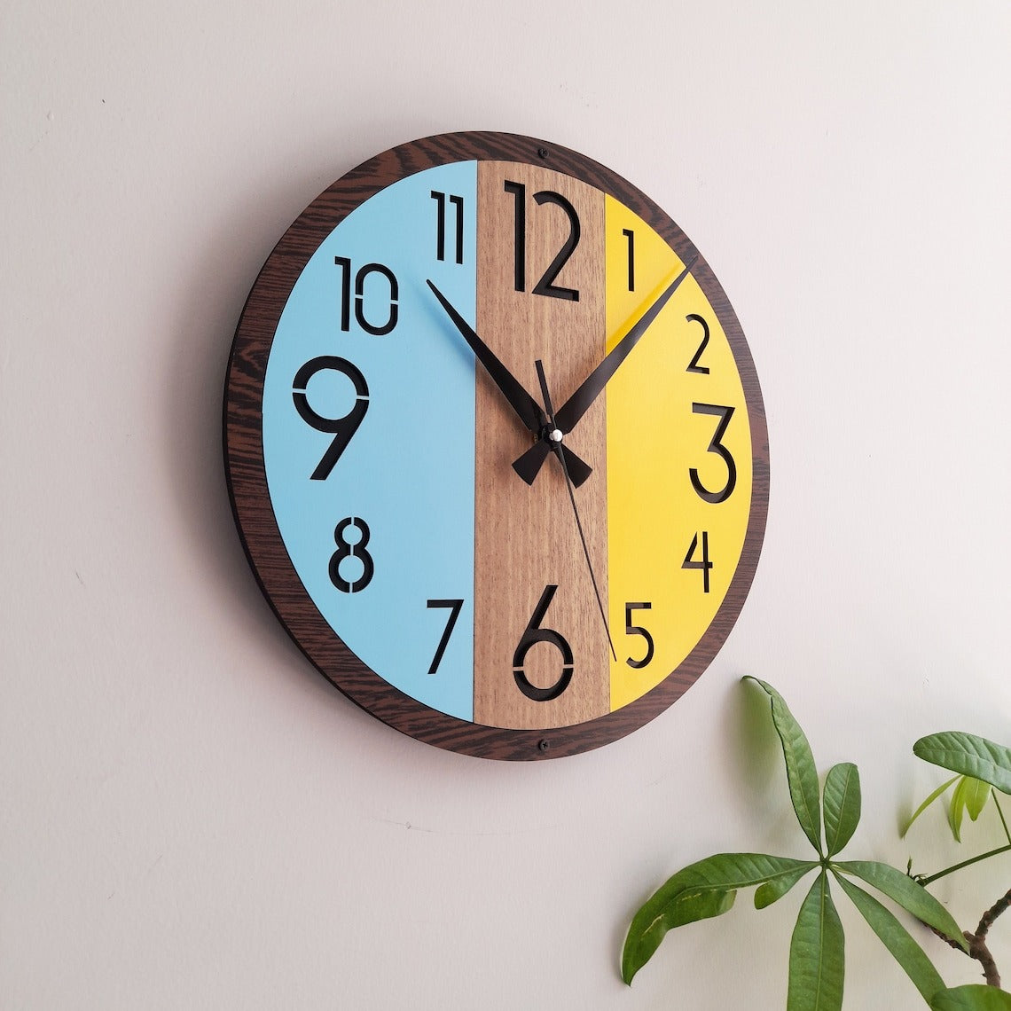 Round wall clock with a wooden frame and colored sections on a light background