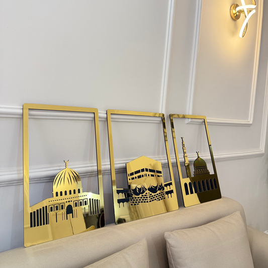 Three gold-framed mirrors with architectural reflections on a white wall above a beige sofa.