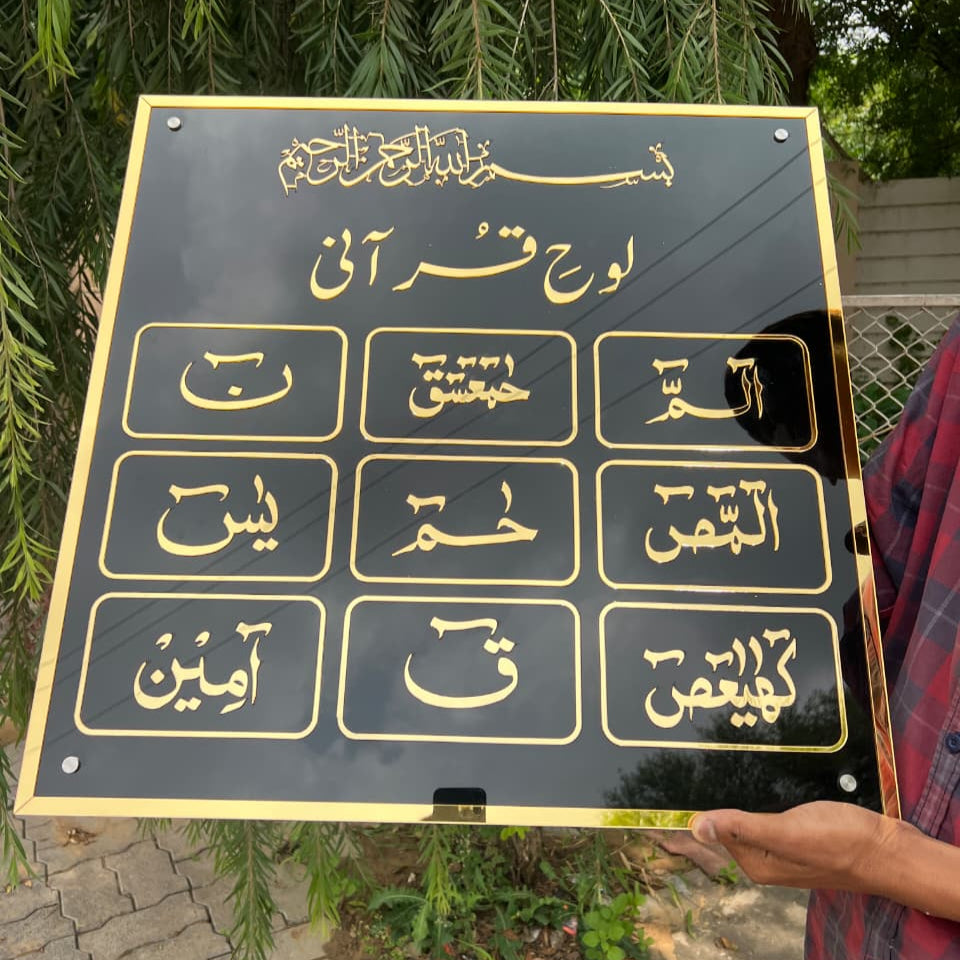 Person holding a black plaque with gold text outdoors