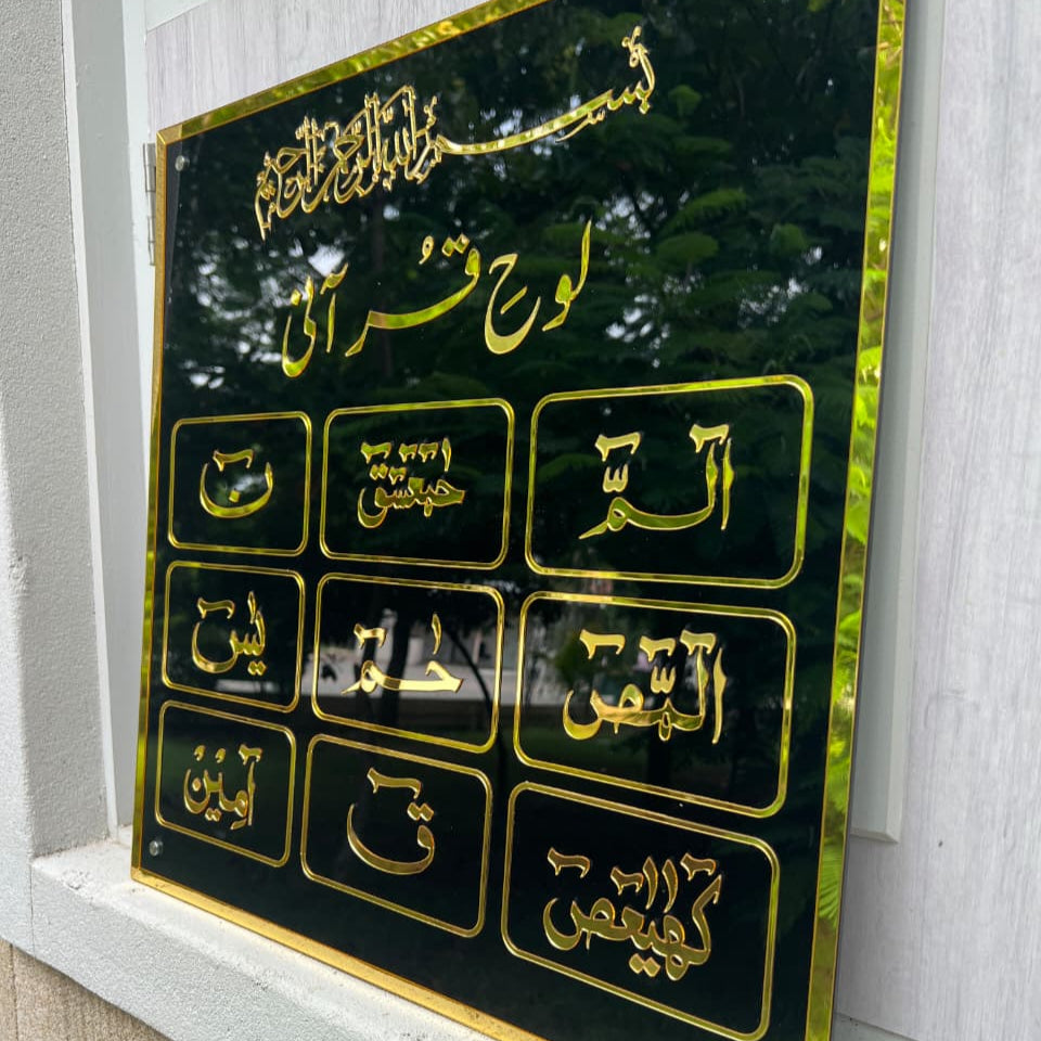 Decorative plaque with Arabic text and gold accents on a black background, mounted on a wall.