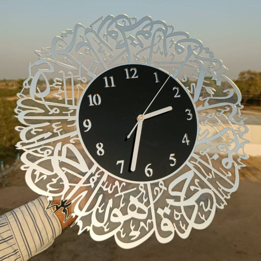 Decorative wall clock with Arabic calligraphy held by a person outdoors.