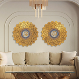 Two circular gold-colored 3D metal wall arts featuring geometric patterns and the Arabic script for 'Asma Ul Husna' mounted on a wall above a beige sofa with cushions.