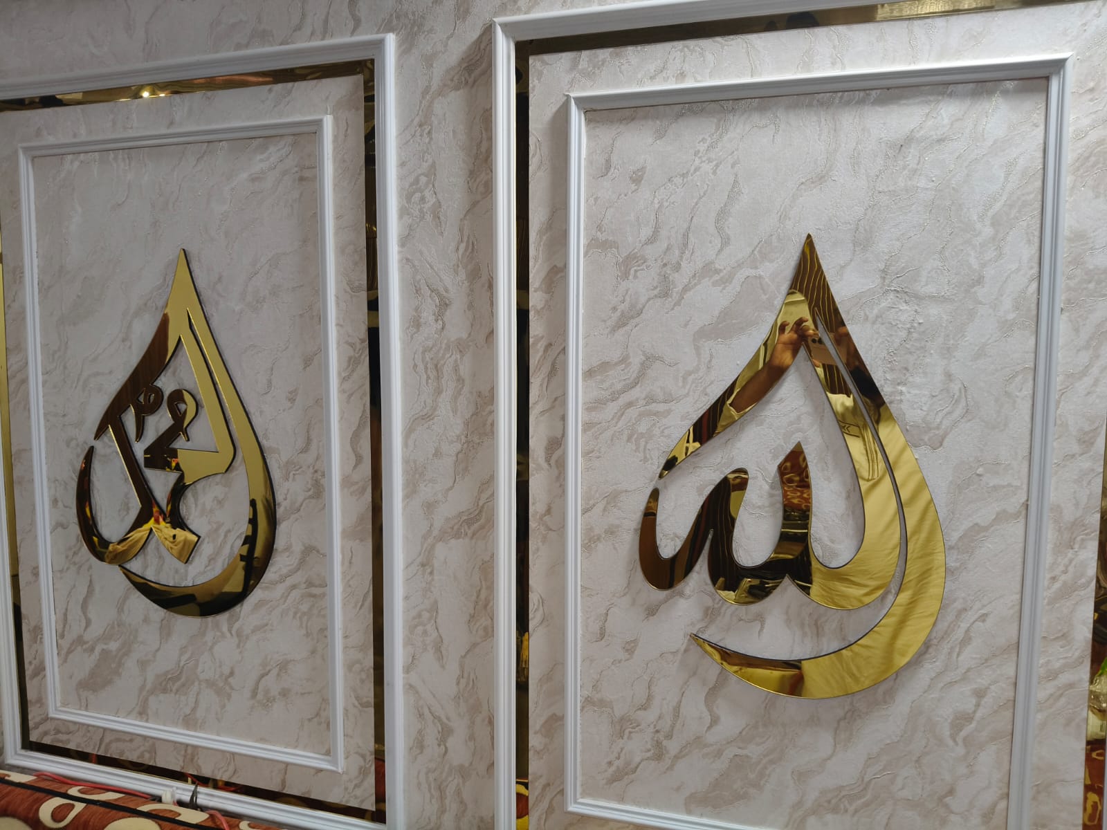 Two framed pieces with gold Arabic calligraphy on a marble-like background