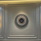 Decorative wall art with a central circular design and Arabic text, flanked by two wall lights on a gray panel.
