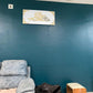 Gray sofa against a teal wall with a decorative plaque featuring Arabic calligraphy.