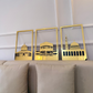 Three gold-framed artworks of architectural designs on a wall above a beige sofa.