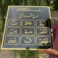 Person holding a black plaque with gold text outdoors