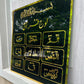 Decorative plaque with Arabic text and gold accents on a black background, mounted on a wall.