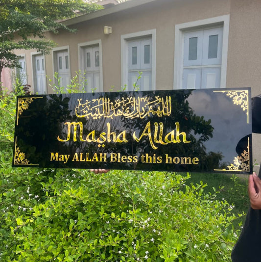 Decorative sign with 'Masha Allah' text held in front of a house.