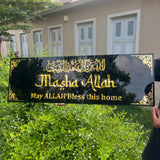 Decorative sign with 'Masha Allah' text held in front of a house.
